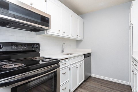 a kitchen with white cabinets and black appliances